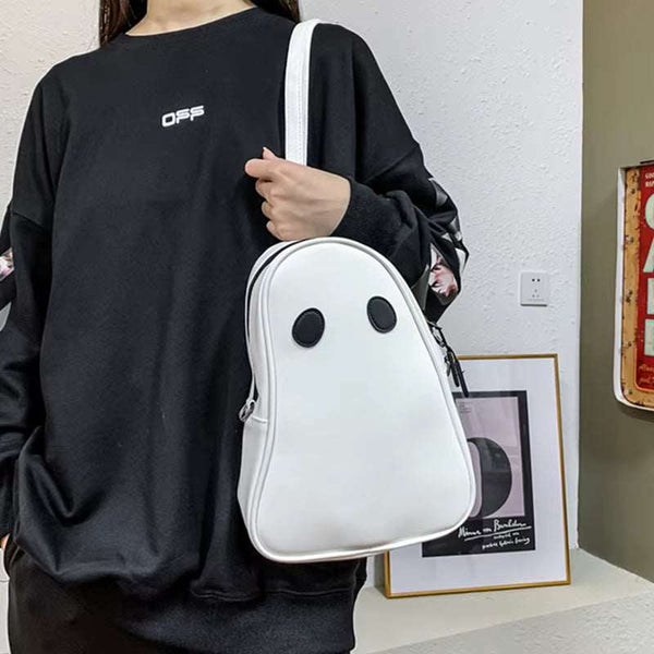 White Halloween cartoon ghost shaped handbag with black eyes worn by a person in a black sweatshirt