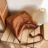 Brown Japanese unisex shoulder bag on wooden surface next to a lamp