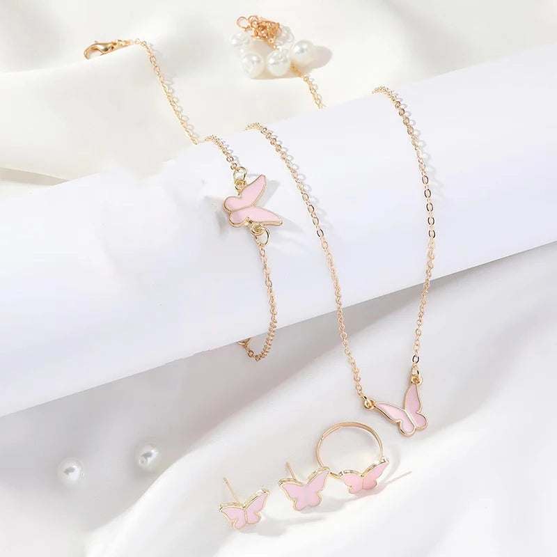 Butterfly pendants necklace set with pink butterfly charms on gold chains including bracelet, ring, and earrings on white background