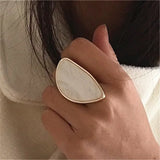 Fashion woman ring with large white stone and gold trim on finger