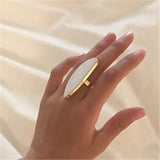 Fashion woman ring with large white oval stone on gold band worn on hand