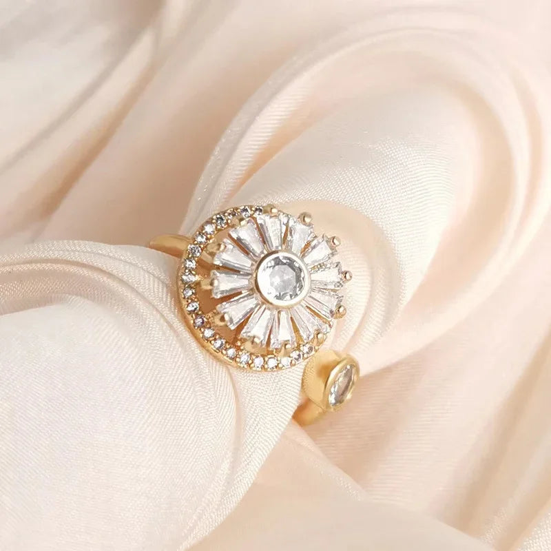 Elegant gold fidget spinner ring with sparkling clear crystals on beige fabric background