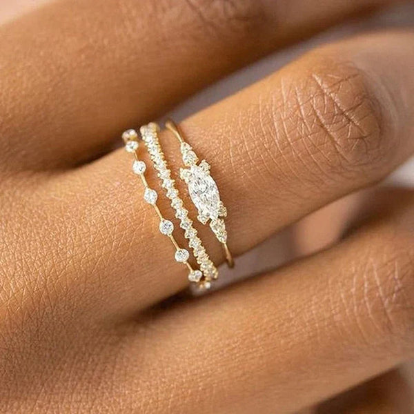 Close-up of hand wearing three delicate stackable gold rings with cubic zirconia stones