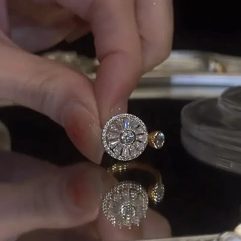 Close-up of a hand holding a sparkling silver fidget spinner ring with a central gem and intricate detailing on a reflective surface