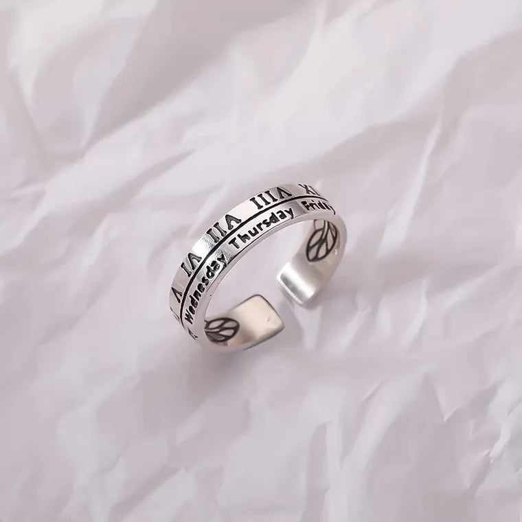 Silver fidget spinner ring with calendar and Roman numerals design on crumpled white background