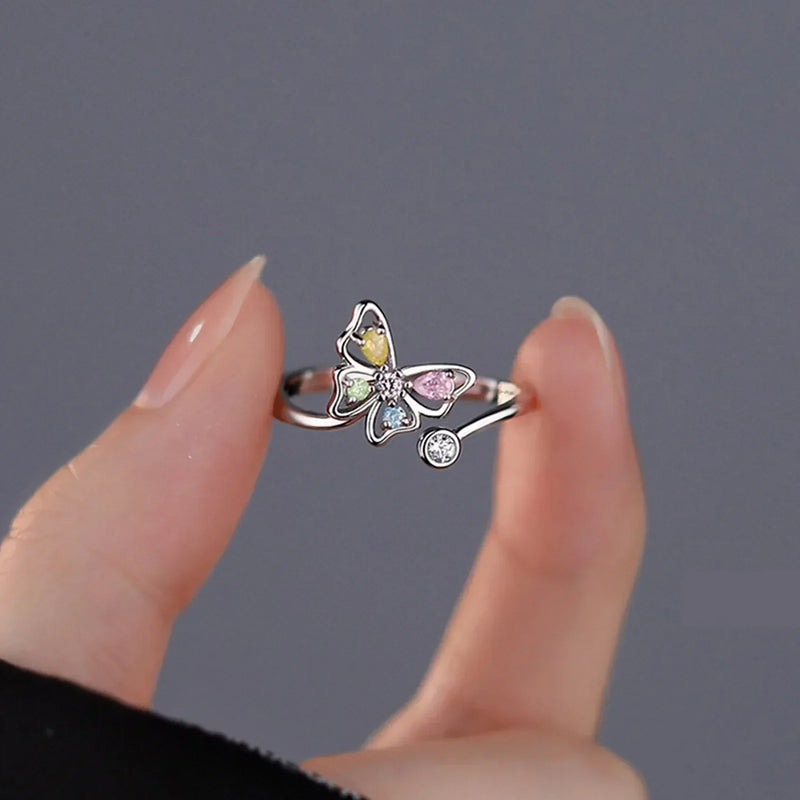 Delicate pink romantic flower ring with multicolored petals and a small zircon stone held between fingers