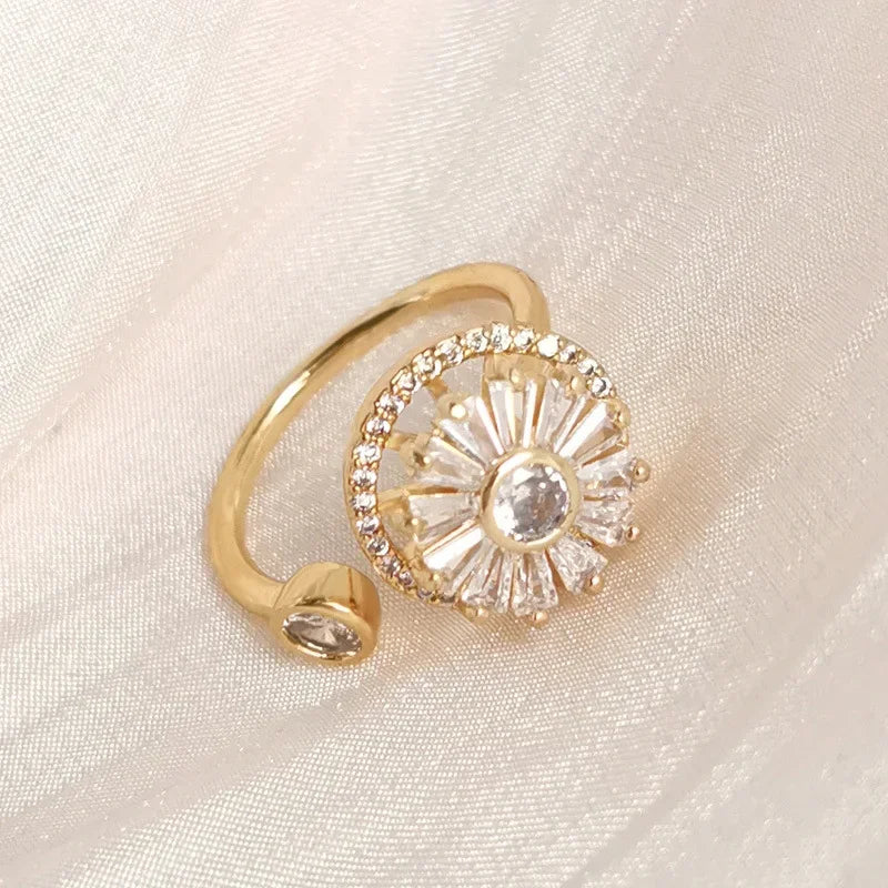 Gold fidget spinner ring with clear crystals on beige fabric background