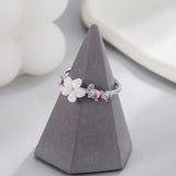 Pink romantic flower ring with white flower and pink zircon stones on gray cone display