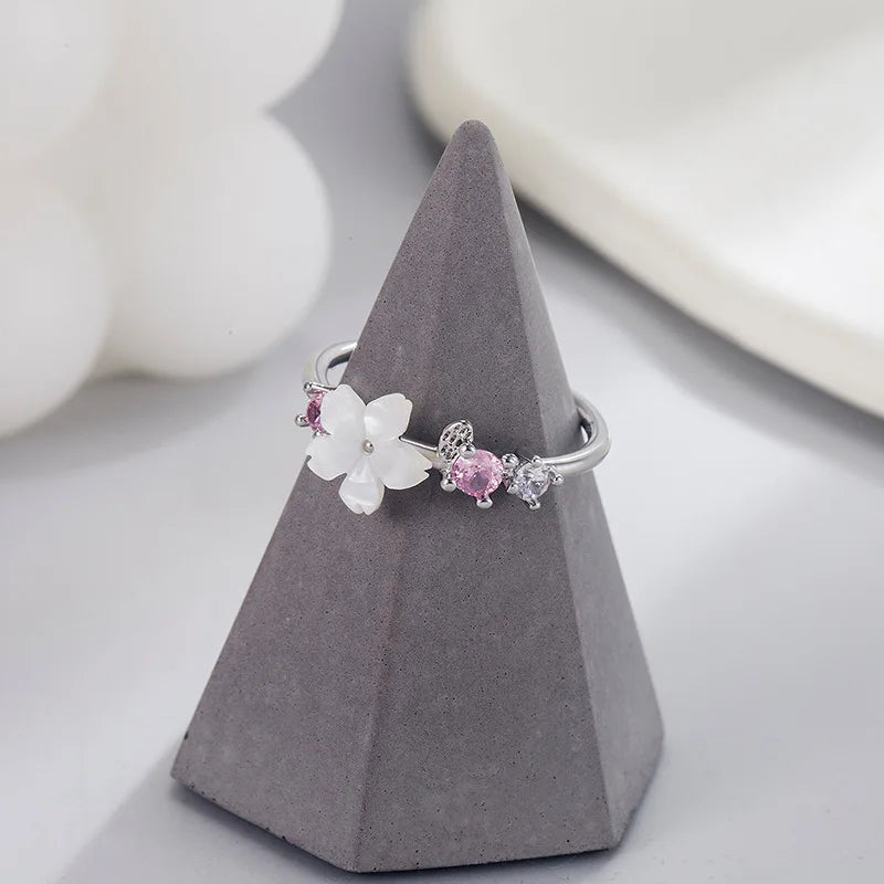 Pink romantic flower ring with white flower and pink zircon stones on gray cone display